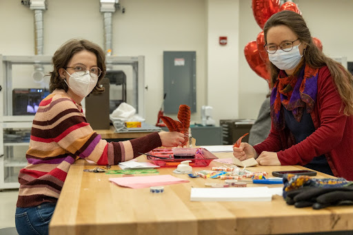 Two visitors write letters using feather quill pens at the Happy Gall-entine’s Day event.