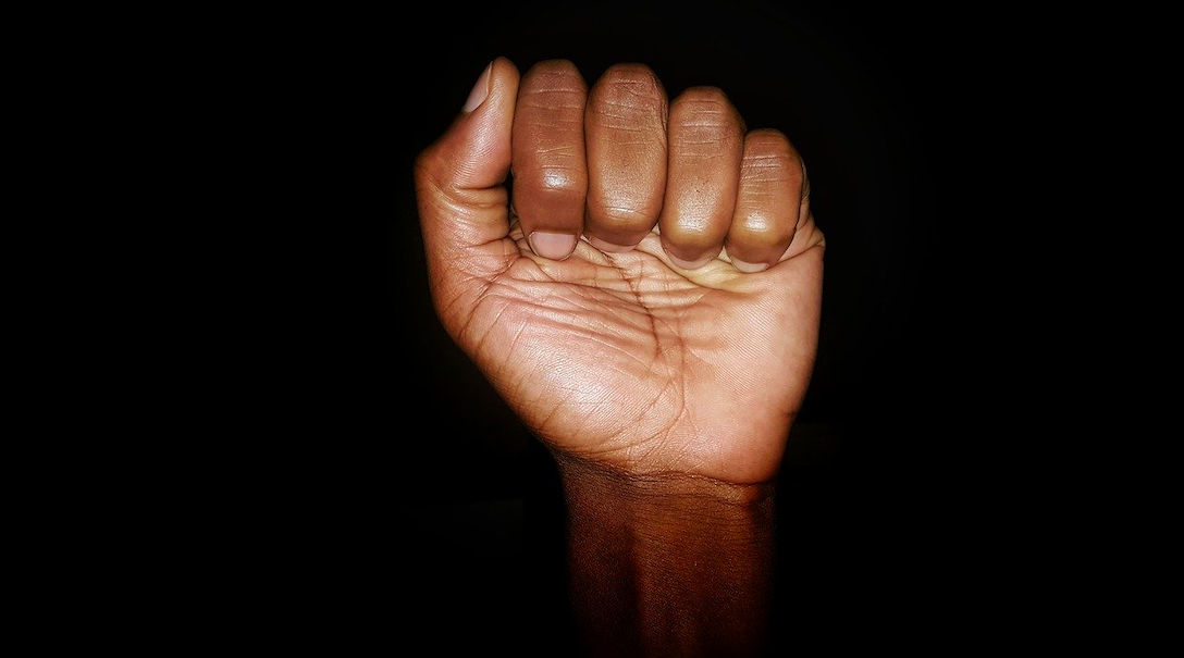 Black person's fist against black background