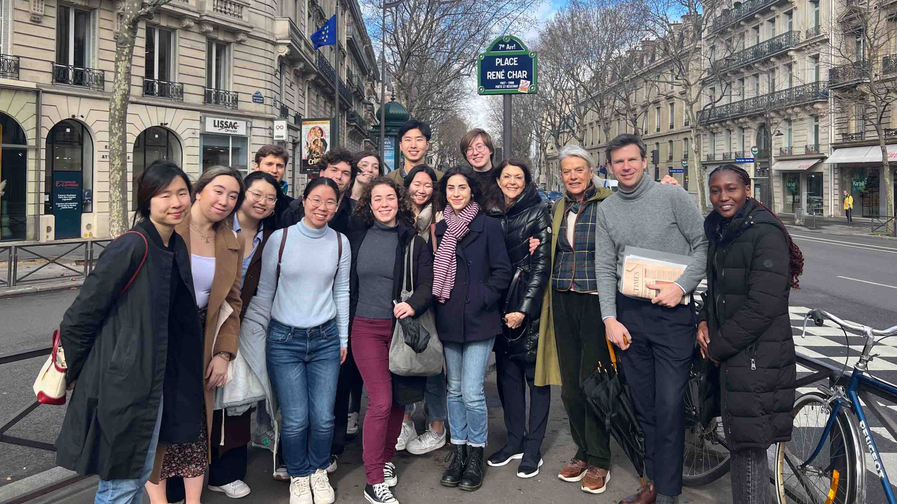 During a spring break trip to France, the group stops in front of the “Place René Char” street sign in central Paris. It reads ’