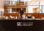 Emma Sarconi smiling behind the table of her inaugural Special Collections Showcase.